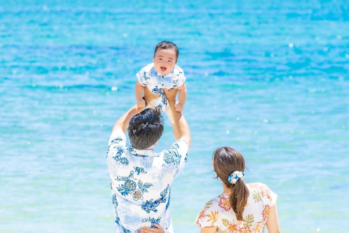かりゆしウェアのパパに高く抱き上げられ笑顔になる赤ちゃん